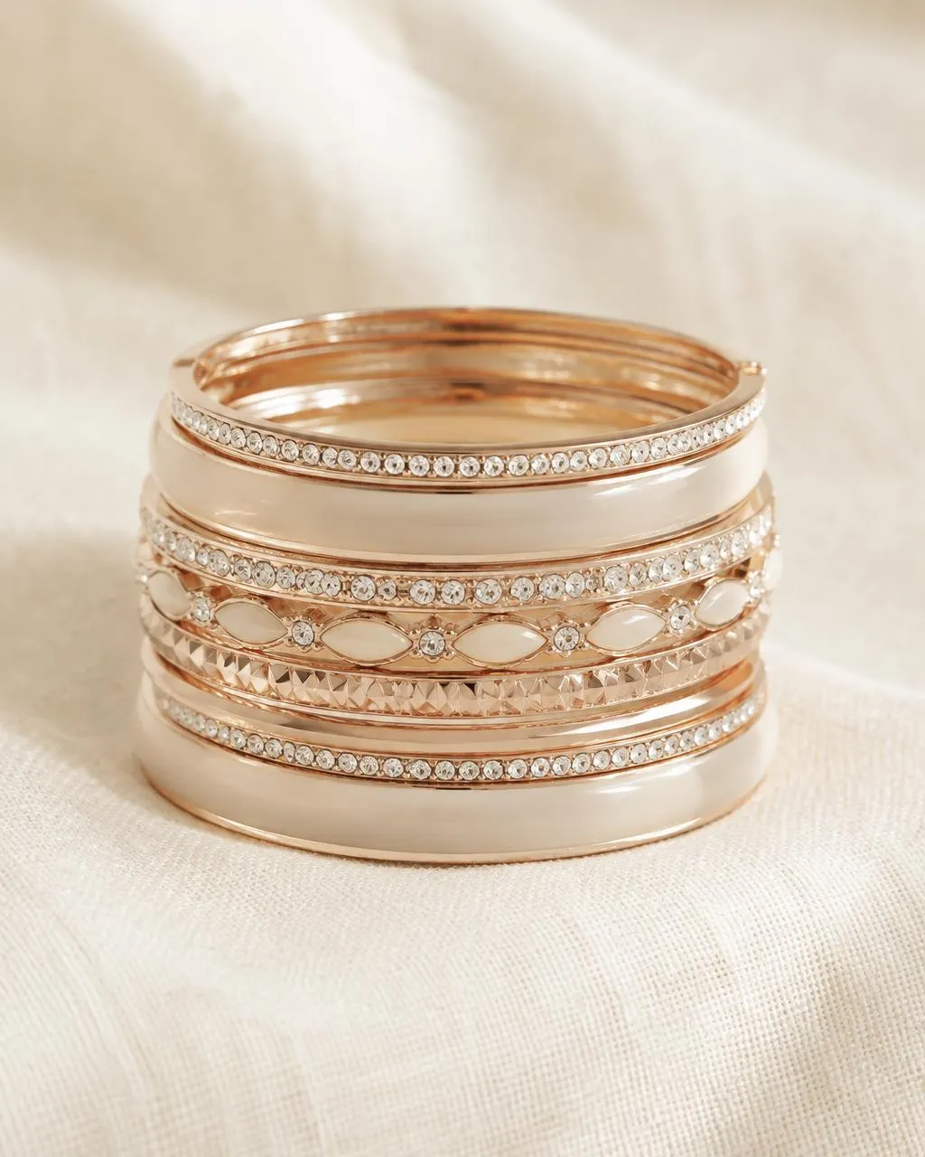 Stack of rose-gold tone bangles with crystals