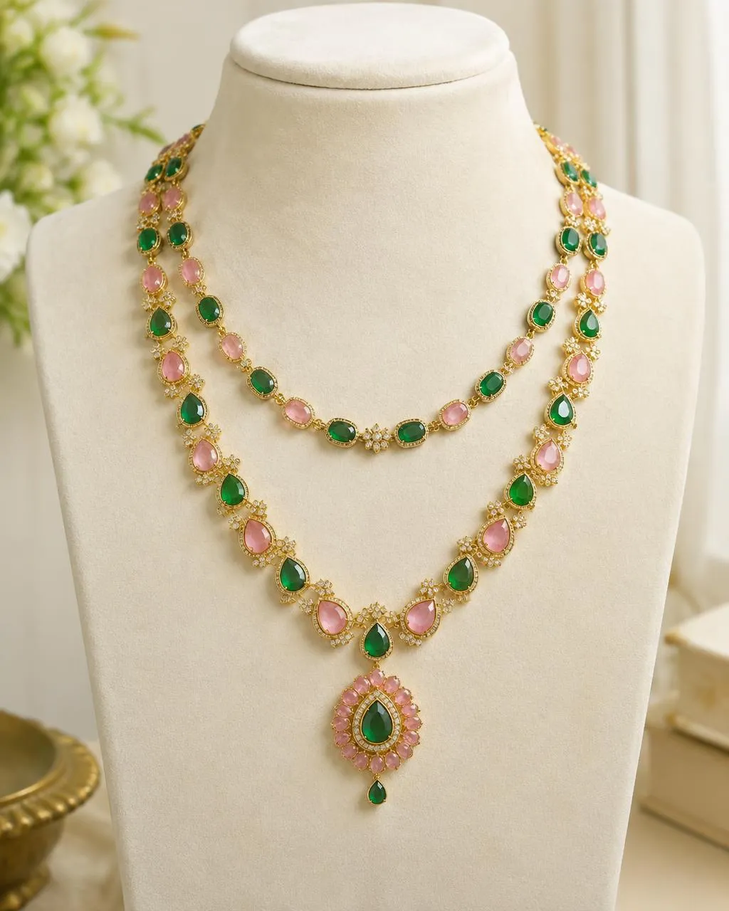 Layered necklace with green and pink stones on an ivory bust